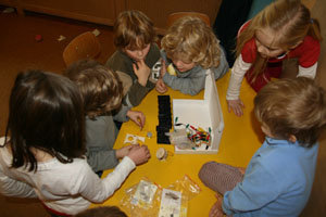 Kindergruppe spielt an einem Tisch mit dem Elektrobaukasten